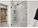 Modern glass-enclosed shower with marble-style tile and closet access at 527 E North St, Indianapolis, IN 46204