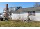 Backyard with second story balcony and propane tank, with overgrown grass and bare tree branches at 13205 E Legal Tender Rd, Columbus, IN 47203