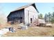 Exterior view of barn showing weathered siding, open doorway, and surrounding vegetation and equipment at 13205 E Legal Tender Rd, Columbus, IN 47203