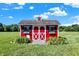 Charming red outbuilding with white trim and decorative shutters in a well-manicured backyard at 13208 State Road 32 E, Noblesville, IN 46060
