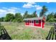 Exterior of a red outbuilding with white trim surrounded by green grass and a wooden fence at 13208 State Road 32 E, Noblesville, IN 46060