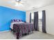 Bright bedroom with a blue accent wall, large window, and colorful striped bedding at 1560 Cold Spring Dr, Brownsburg, IN 46112