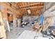 Cluttered garage interior showing exposed wooden beams, a stained floor and diverse storage at 3612 Schofield Ave, Indianapolis, IN 46218