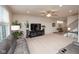 Open-concept living room features a gray sectional, ceiling fan, and natural light, flowing to the staircase at 6748 Fallen Leaf Dr, Whitestown, IN 46075