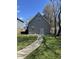 View of backyard with small lawn, concrete walkway, and access door on a sunny day at 1702 Barth Ave, Indianapolis, IN 46203