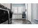 Modern laundry room features gray herringbone floors, white cabinets and modern washer and dryer units at 340 Beechwood Farm Ln, Indianapolis, IN 46260