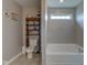 Bathroom with a toilet with shelves and a large soaking tub by the window at 11851 Fawn Crest Dr, Indianapolis, IN 46235