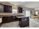Large kitchen with stainless steel appliances, dark cabinets, island and wood flooring, with adjacent dining and living areas at 11851 Fawn Crest Dr, Indianapolis, IN 46235