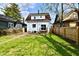 A backyard featuring a grassy lawn, partial fencing, and a home with a small back porch at 3634 N Kenwood Ave, Indianapolis, IN 46208