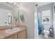 Bright bathroom featuring a single sink vanity, a shower with blue curtains and a window at 2434 N Pennsylvania St, Indianapolis, IN 46205