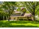 Back exterior view of a two-story home showcasing a well-kept lawn, stone accents, and mature trees at 725 Sugarbush Dr, Zionsville, IN 46077