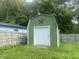 Backyard storage shed with roll up garage door and fenced in yard at 6438 Doris Dr, Indianapolis, IN 46214