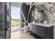 Stylish bathroom features a black vanity, modern fixtures, and an open door with a view of the yard at 9700 Windy Hills Dr, Zionsville, IN 46077