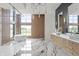Stunning bathroom featuring a soaking tub, luxurious marble floors, and a view of the outdoors through large windows at 9700 Windy Hills Dr, Zionsville, IN 46077