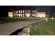 Night view of a modern mixed material home featuring exterior lighting and a long driveway at 9700 Windy Hills Dr, Zionsville, IN 46077
