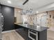 Open concept kitchen featuring black cabinets, stainless steel appliances, and a large center island with unique light fixture at 9700 Windy Hills Dr, Zionsville, IN 46077