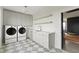 Bright laundry room with gray cabinets, shelving, and modern washer and dryer units at 9700 Windy Hills Dr, Zionsville, IN 46077