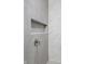 Close-up of modern shower features white tile, marble-look accent tile, stainless steel fixtures, and a recessed shelf at 9700 Windy Hills Dr, Zionsville, IN 46077