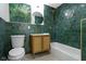 A stylish bathroom with green tile, a vanity with a round mirror, and a bathtub with gold fixtures at 2936 N New Jersey St, Indianapolis, IN 46205