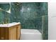 A bathroom with a rattan vanity, gold fixtures, and a shower over a bathtub with green tiling at 2936 N New Jersey St, Indianapolis, IN 46205