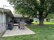 This patio features outdoor seating and a barbecue, all shaded by a mature tree at 105 Tulip Dr, Indianapolis, IN 46227