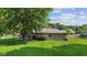 A backyard with a green lawn, patio, trees, and garden at 105 Tulip Dr, Indianapolis, IN 46227
