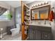 Gray bathroom with a vanity with cabinets, mirror, white toilet and window at 105 Tulip Dr, Indianapolis, IN 46227