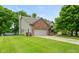 Exterior view of home featuring a brick front, attached two-car garage, large yard and mature trees at 1936 Broadmoor Ln, Columbus, IN 47203