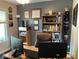 A well-appointed home office showcasing a large desk, book-filled shelves, diplomas, and natural light at 5964 Laramie Trl, Columbus, IN 47203