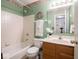 Bathroom featuring white tiled walls, shower-tub combo, and oak vanity with decorative green wall paint at 7119 Topp Creek Ct, Indianapolis, IN 46214