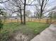 Fenced backyard with a grassy area, mature trees, and concrete patio at 2869 Stuart St, Indianapolis, IN 46218
