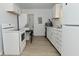 Well-lit kitchen featuring white appliances, countertops, and cabinets with a laundry area in the background at 3111 Station St, Indianapolis, IN 46218