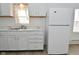 Bright kitchen featuring white appliances, countertops, and cabinets with a laundry area in the background at 3111 Station St, Indianapolis, IN 46218