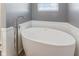 A large soaking tub with a modern faucet sits beneath a bright window in this updated bathroom at 3335 Hurst St, Whiteland, IN 46184