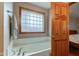 Close-up of bright bathroom featuring jetted tub with chrome fixtures, neutral colors, and a window at 691 Walnut Woods Dr, Greenwood, IN 46142