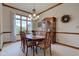Dining room with wooden table, hutch, large window with natural light, and elegant chandelier at 691 Walnut Woods Dr, Greenwood, IN 46142