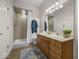 Bathroom with tiled shower, wood vanity, large mirror, and neutral decor at 9943 Irishman'S Run Ln, Zionsville, IN 46077