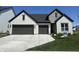 Charming two-story home boasts a white brick facade, stone accents, a dark roof, and a two-car garage at 4982 Reavie Ct, Noblesville, IN 46062