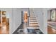 Elegant entryway with slate tile flooring, wooden staircase, and views into the living and dining areas at 4807 Graceland Ave, Indianapolis, IN 46208