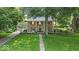 Two-story stone home features a manicured lawn, mature trees, attached garage, and walkway to covered front porch at 4807 Graceland Ave, Indianapolis, IN 46208