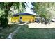 Backyard featuring a yellow house with ladder, table, and chair amongst lush trees at 850 S Holmes Ave, Indianapolis, IN 46221