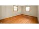 Bedroom features gleaming hardwood floors, two bright windows, and neutral walls at 1504 N Knightstown Rd, Shelbyville, IN 46176