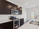 Well-lit kitchen showcases stainless steel appliances, dark cabinetry, and a double basin sink in the kitchen island at 6286 Wasco Dr, Whitestown, IN 46075
