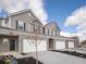 Eye-level exterior view of the townhomes with gray siding, brick accents, black shutters, and concrete driveways at 6304 Wasco Dr, Whitestown, IN 46075