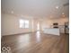 Open-concept living area with wood-look flooring, white walls, and a modern kitchen in the background at 6304 Wasco Dr, Whitestown, IN 46075