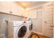 Bright laundry room includes washer, dryer, cabinets, and a door to separate the space at 1220 Greenwood Station Blvd, Greenwood, IN 46143