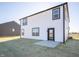 Rear exterior view of home featuring white vinyl siding, black trim, and a concrete patio at 7888 Magnolia St, New Palestine, IN 46163