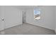 A bright bedroom with gray carpet and a view of rooftops through a window at 5143 Rolling Meadow Blvd, Indianapolis, IN 46237