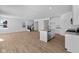 Bright and open floor plan with a kitchen island, white cabinets, stainless appliances, and light wood-look floors at 5143 Rolling Meadow Blvd, Indianapolis, IN 46237