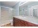 Bright bathroom featuring a wood vanity, large mirror and a shower and bathtub combo with sliding glass doors at 6840 Minnow Dr, Indianapolis, IN 46237